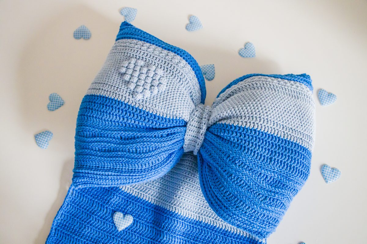 dark and light blue crochet bow with tiny hearts around it