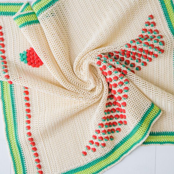 cream crochet blanket with strawberry detail and green edging