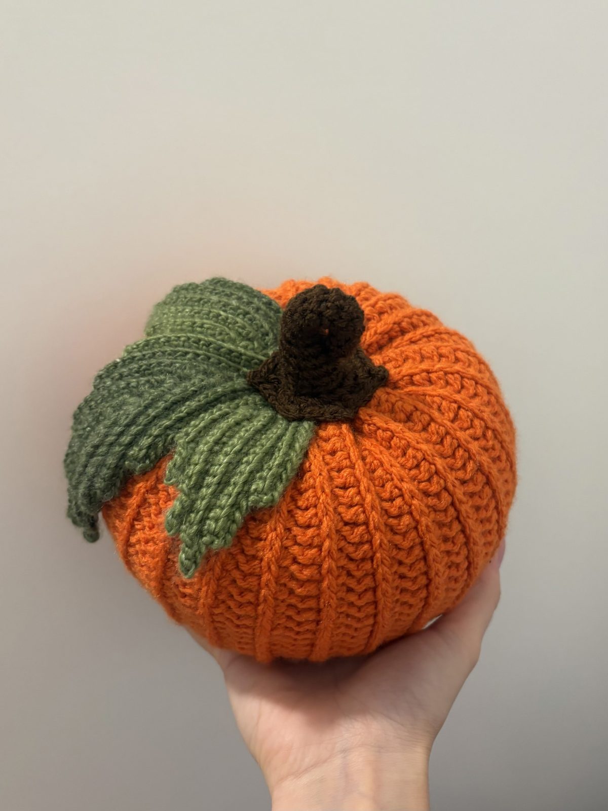 hand holding crochet pumpkin with leaf