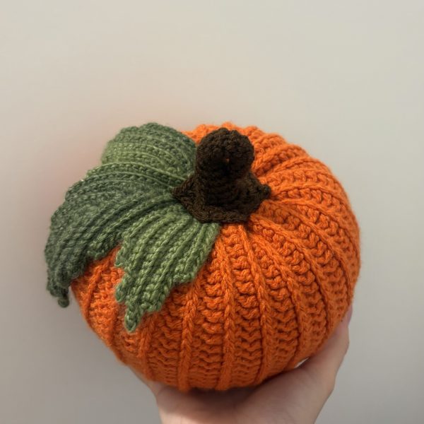hand holding crochet pumpkin with leaf